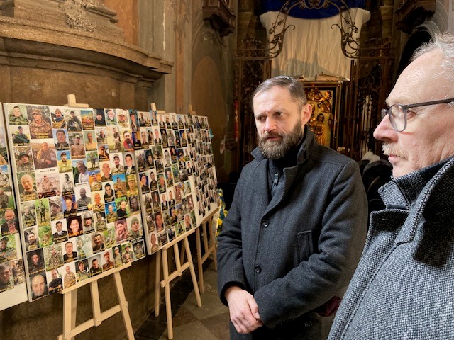 Zwei Männer schauen auf eine Wand von Bildern mit Porträtbildern
