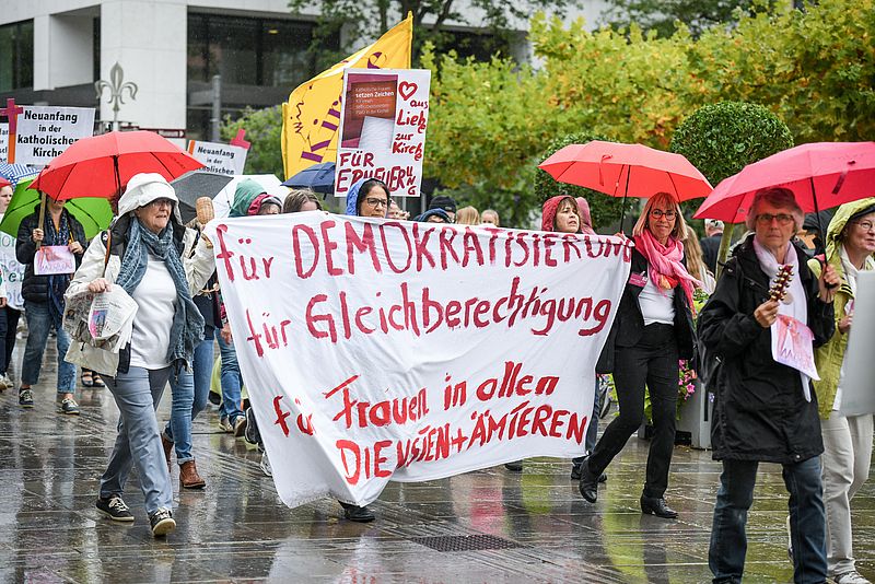 Menschen demonstrieren am 26. September 2019 in Fulda für Frauenrechte in der katholischen Kirche. Sie tragen ein großes Banner mit der Aufschrift "Für Demokratisierung - Für Gleichberechtigung - Für Frauen in allen Diensten + Ämtern"