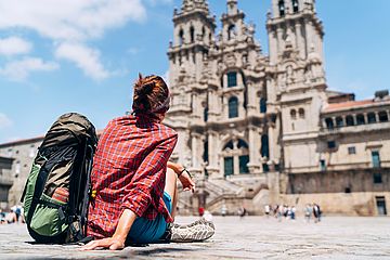 Pilgerin sitzt auf dem Obradeiro-Platz in Santiago de Compostela