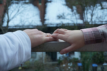 Zwei Hände mit Eheringen berühren sich. 