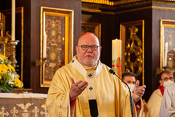 Kardinal Reinhard Marx mit ausgebreiteter Armen in einer Kirche