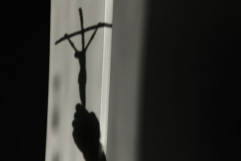 Hand hält Kreuz im Schatten