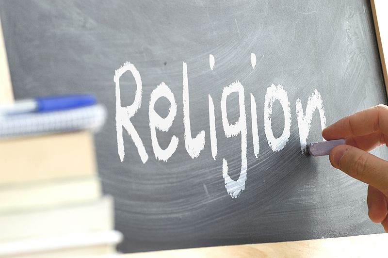 Auf Tafel wird Wort "Religion" mit Kreide geschrieben