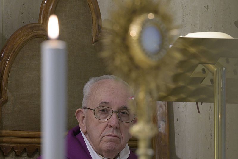 Papst Franziskus im Hintergrund, im Vordergund eine Kerze und das Allerheiligste