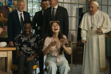 Junge Menschen lachen, Papst steht neben ihnen, im Hintergrund Männer in dunklen Anzügen