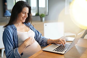 Schwangere Frau vor Computer