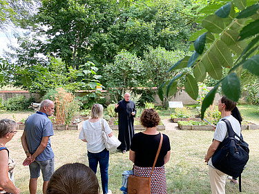 Besucher und ein Benediktiner der bayerischen Abtei Münsterschwarzach im Garten des ehemaligen Klosters Memleben.