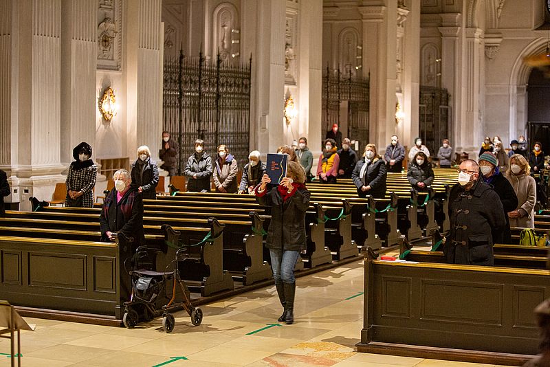 Hiltrud Schönheit, Vorsitzende des Münchner Katholikenrats, trägt das neue Trauerbuch durch den Mittelgang in St. Michael nach vorne.
