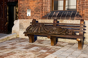 Bronze-Statue einer Person, die auf einer Bank liegt