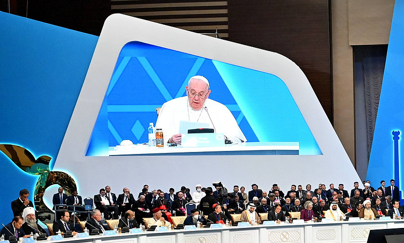 Papst Franzikus auf einer Leinwand, davor sitzen andere Religionsvertreter.