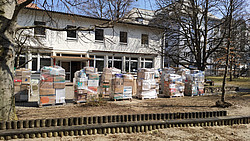 Gestapelte Kisten befüllt mit Lebensmittel- und Kleiderspenden vor dem ehemaligen Kindergarten St. Wolfgang.