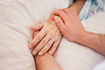 Hände im Krankenbett werden gehalten