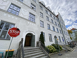 Schulgebäude des Edith-Stein-Gymnasium in München-Haidhausen. Davor steht ein Schild mit der Aufschrift "Stop Umweltverschmutzung"