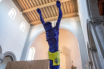 Ein blauer Jesus-Körper aus Holz hängt im Altarraum der Kirche.