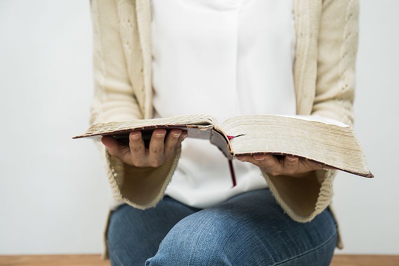 Frau hält aufgeschlagene Bibel in den Händen