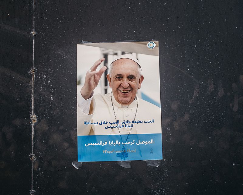 Ein Poster mit einem Bild von Papst Franziskus vor seinem Besuch im Irak hängt am 3. März 2021 in einer Straße in Mossul.