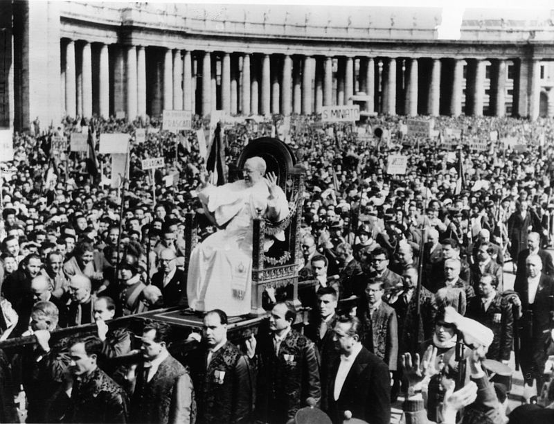 Schwarz-Weiß-Aufnahme: Papst Pius XII. segnet die Menschen auf dem Petersplatz in Rom. 