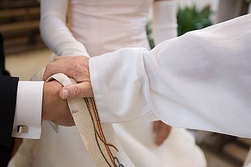 Hände von Priester und Brautpaar