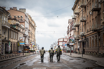 Drei Männer, ukrainische Freiwillige der Territorialverteidigung, gehen am 9. März 2022 in Odessa (Ukraine) eine menschenleere Straße entlang.