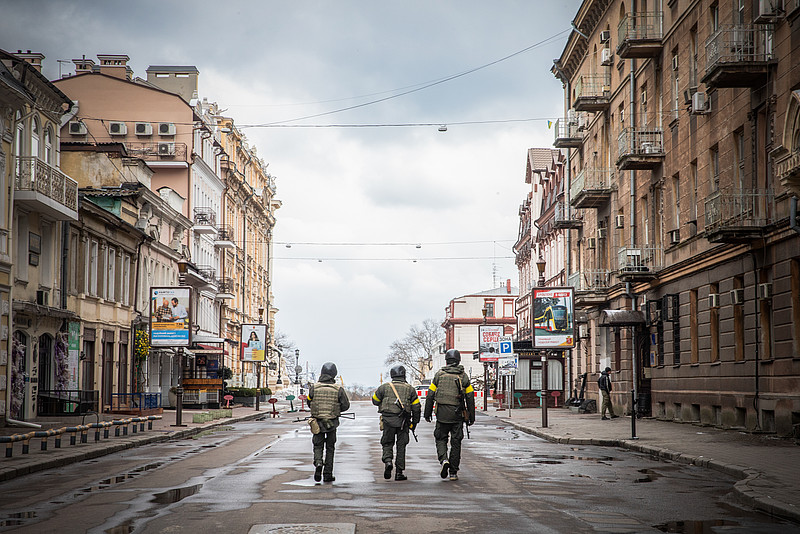 Drei Männer, ukrainische Freiwillige der Territorialverteidigung, gehen am 9. März 2022 in Odessa (Ukraine) eine menschenleere Straße entlang.