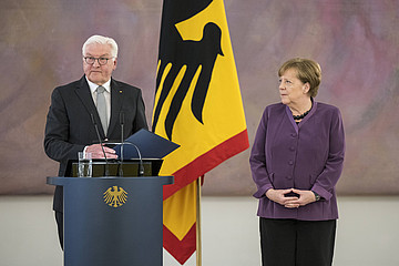 Steinmeier am Rednerpult stehend, daneben Merkel.