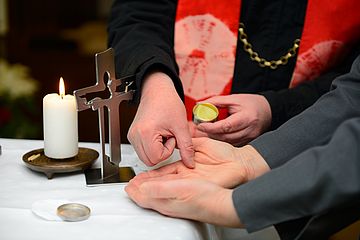 Priester salbt Mann die Hände