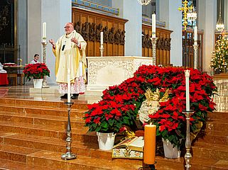 Kardinal Marx im Liebfrauendom, im Vordergrund Jesusfigur umrahmt von Weihnachtssternen