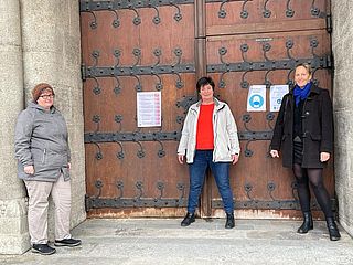 Annemarie Auer, Elisabeth Stanggassinger, Anna Eichlinger vor dem Thesenpapier der Kirche Sankt Rupert in München.