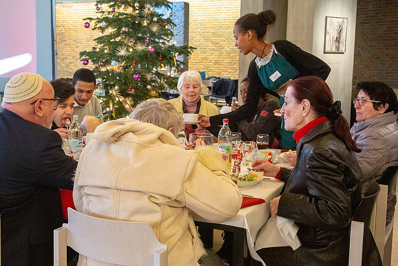 Tisch mit bedürftigen Menschen bei einem gemeinsamen Weihnachtsmahl