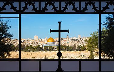 Blick auf Jerusalem durch Kirchenfenster mit Kreuz
