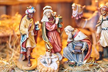 Krippendarstellung: Die Heiligen Drei Könige knien um das Jesuskind.