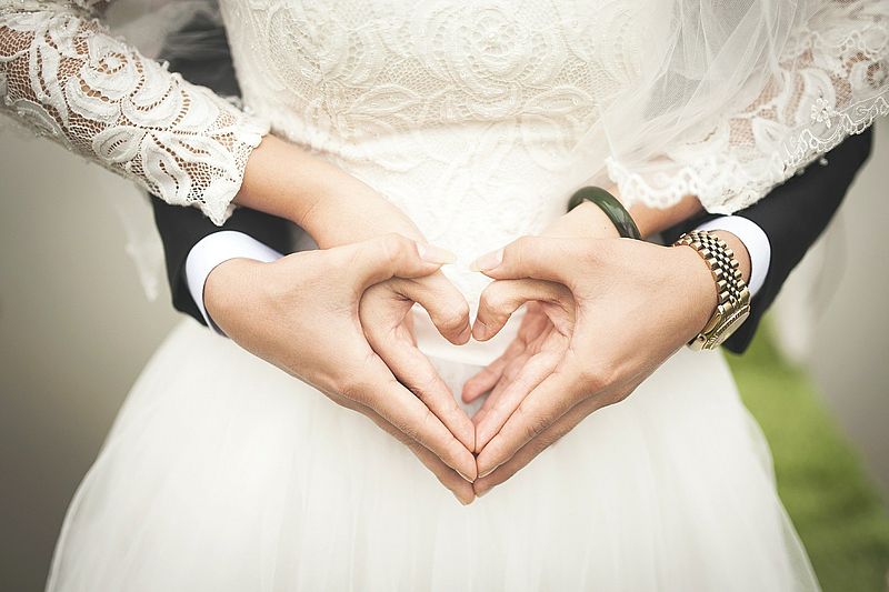 Braut und Bräutigam formen ihre Hände zu einem Herz.