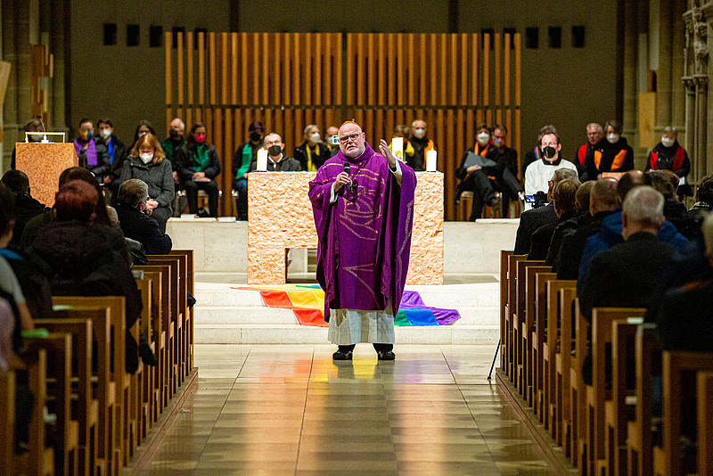Kardinal Marx predigt beim Queer-Gottesdienst. Hinter ihm ist eine Regenbogenflagge zu sehen.