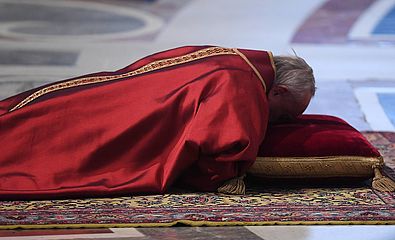 Papst Franziskus liegt ausgestreckt auf dem Boden
