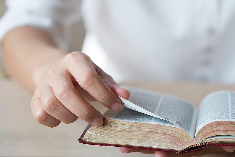 Eine Hand, die in der Bibel blättert
