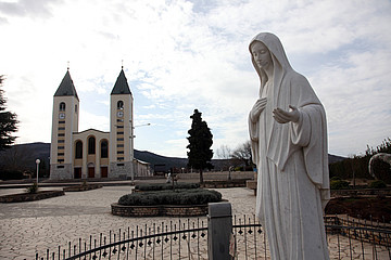 Kirchen im Hintergrund und im Vordergrund eine Marienfigur