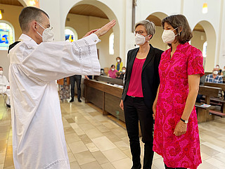 Priester segnet zwei Frauen