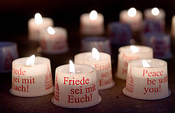 Kerzen mit dem Aufdruck "Friede sei mit euch!" brennen im Gebet als Zeichen des Friedens.