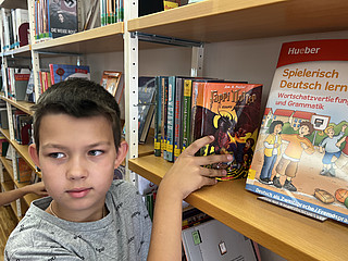 Der neunjährige Kiprian aus Kiew muss sich zwischen einer ukrainischen Harry Potter-Ausgabe und einem Deutschlehrbuch entscheiden. 