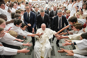 Ministranten aus Frankreich strecken die Hände aus, während Papst Franziskus im Rollstuhl an ihnen vorbeifährt.