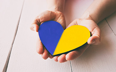Hände halten Herz in blau-gelb