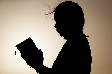 Silhouette einer betenden Frau vor beigem Hintergrund
