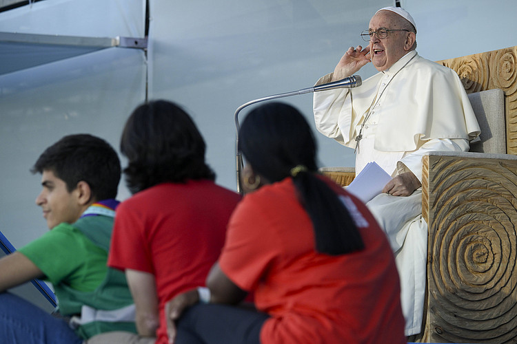 Papst Franziksus hält sich Hand ans Ohr, davor Jugendliche