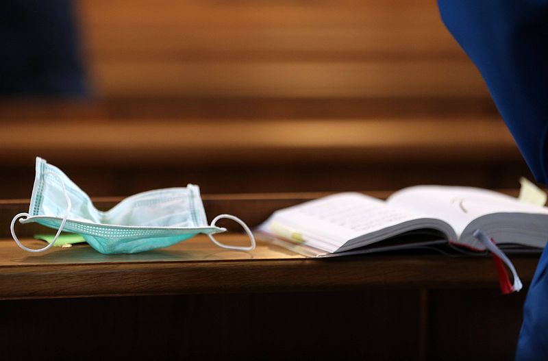 Mundschutz und Gotteslob auf Kirchenbank