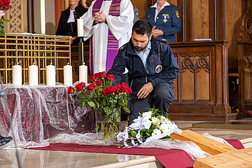 Feuerwehrseelsorger legt Rose vor dem Altar und den fünf Kerzen für die Verstorbenen ab.