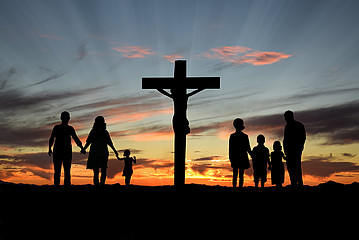 Kreuz vor Sonnenuntergang, daneben die Silhouetten von Erwachsenen und Kindern