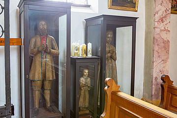In der Wallfahrtskirche stehen drei lebensgroße Wachsfiguren: ein Kind, eine Frau und ein Mann.