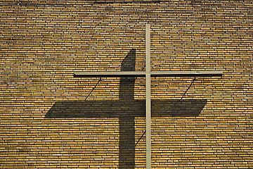 Kreuz wirft Schatten an Ziegelwand