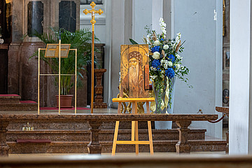 Staffelei mit Ikone aus beschädigtem Holz steht vor Altarraum.