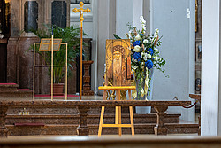 Staffelei mit Ikone aus beschädigtem Holz steht vor Altarraum.
